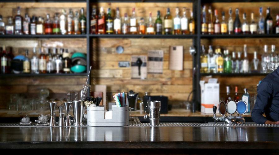 Stocked bar with various bottles and bartender tools.