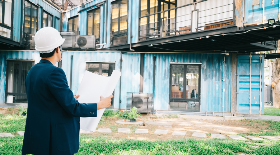 Architect examines blueprint for shipping container building.