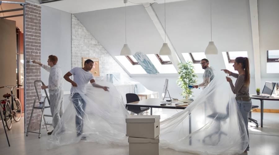 Office renovation with workers moving furniture.