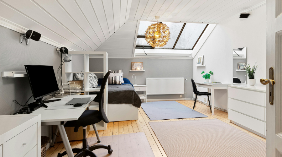 Cozy attic bedroom with desk under skylight.