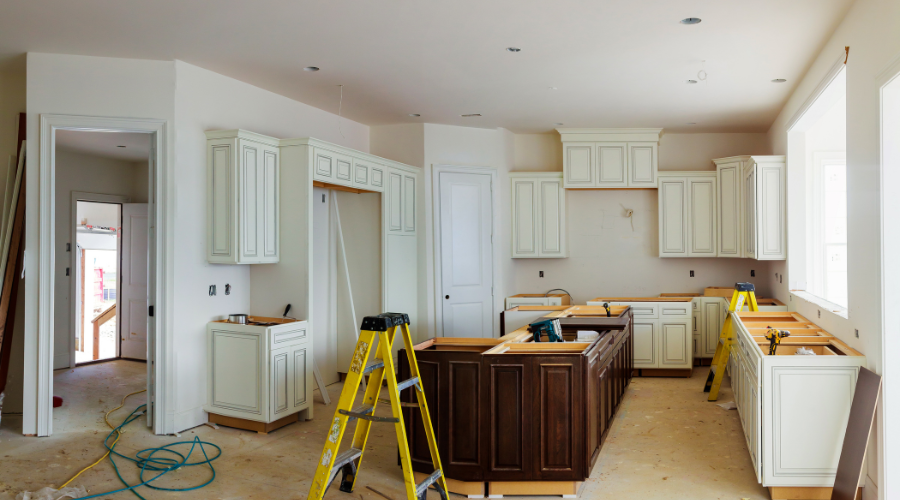 Modern kitchen under renovation with white cabinets.
