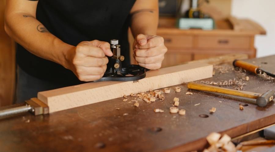 Person woodworking with hand planer on bench