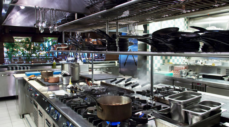 Commercial kitchen with pots and pans on stoves.
