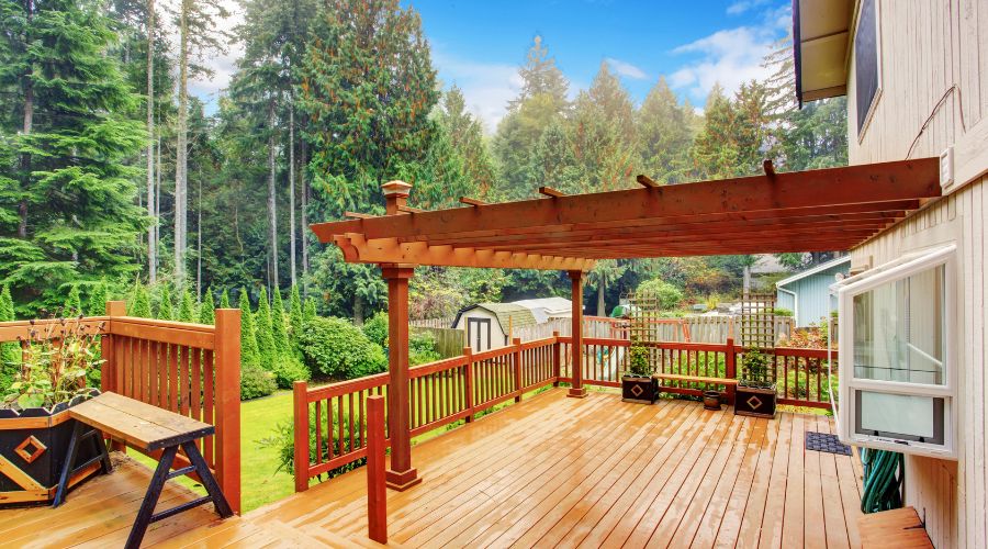 Spacious wooden deck overlooking lush garden and trees.